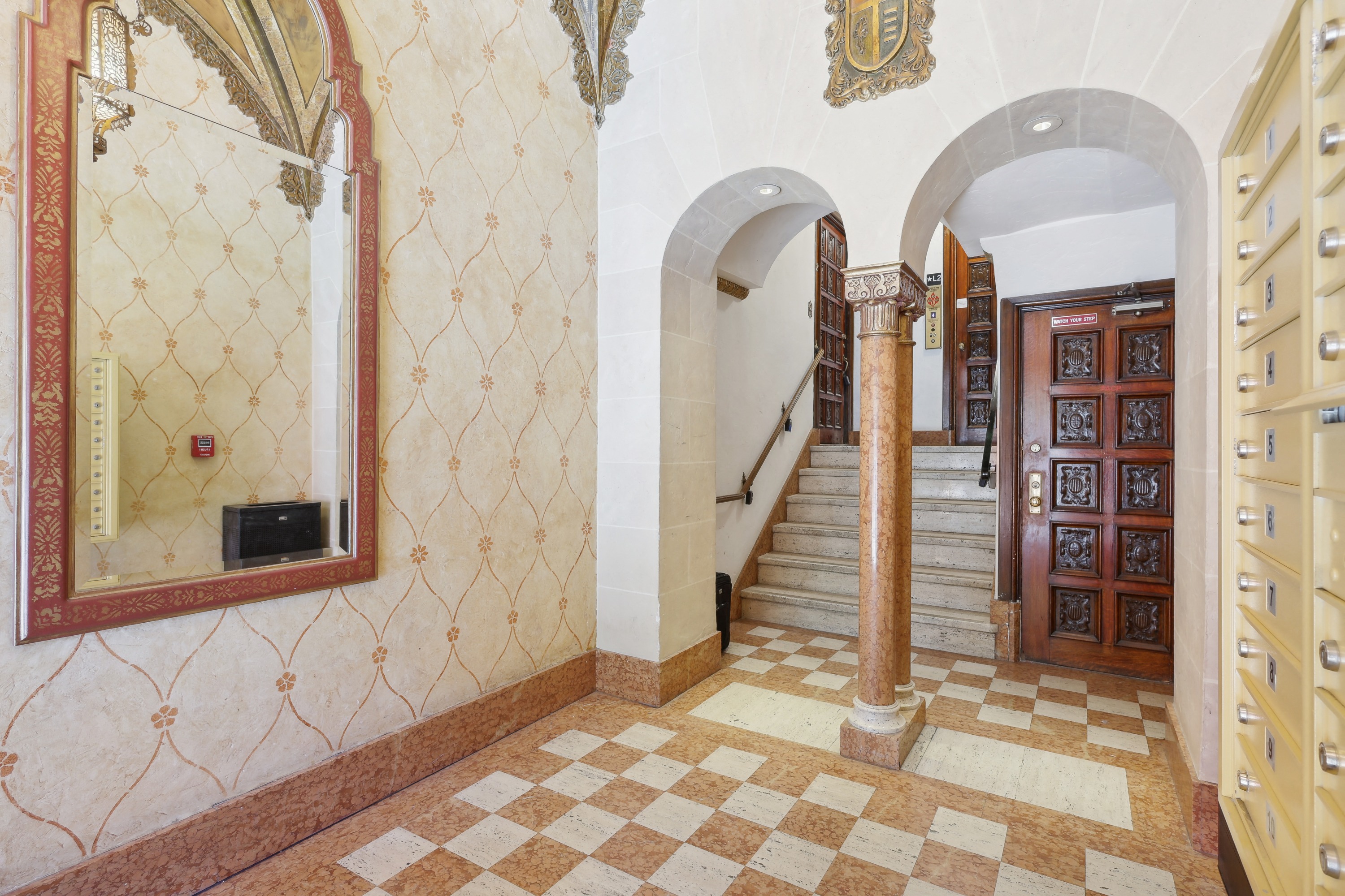 Hallway with a high ceiling and a large mirror with a wooden door